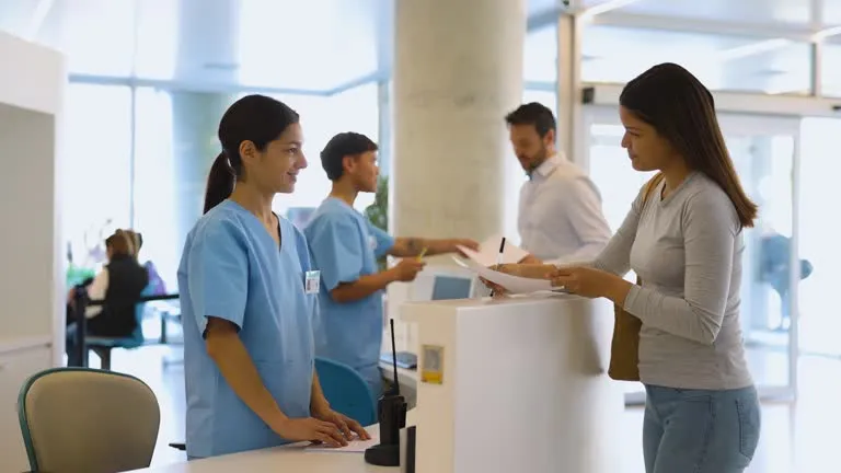 Female patient speaking with receptionist at a medical office for a same-day appointment.
